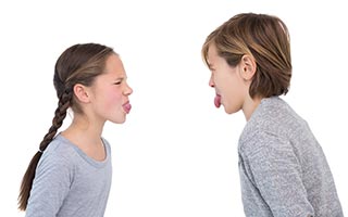 Children sticking their tongue out in a fight